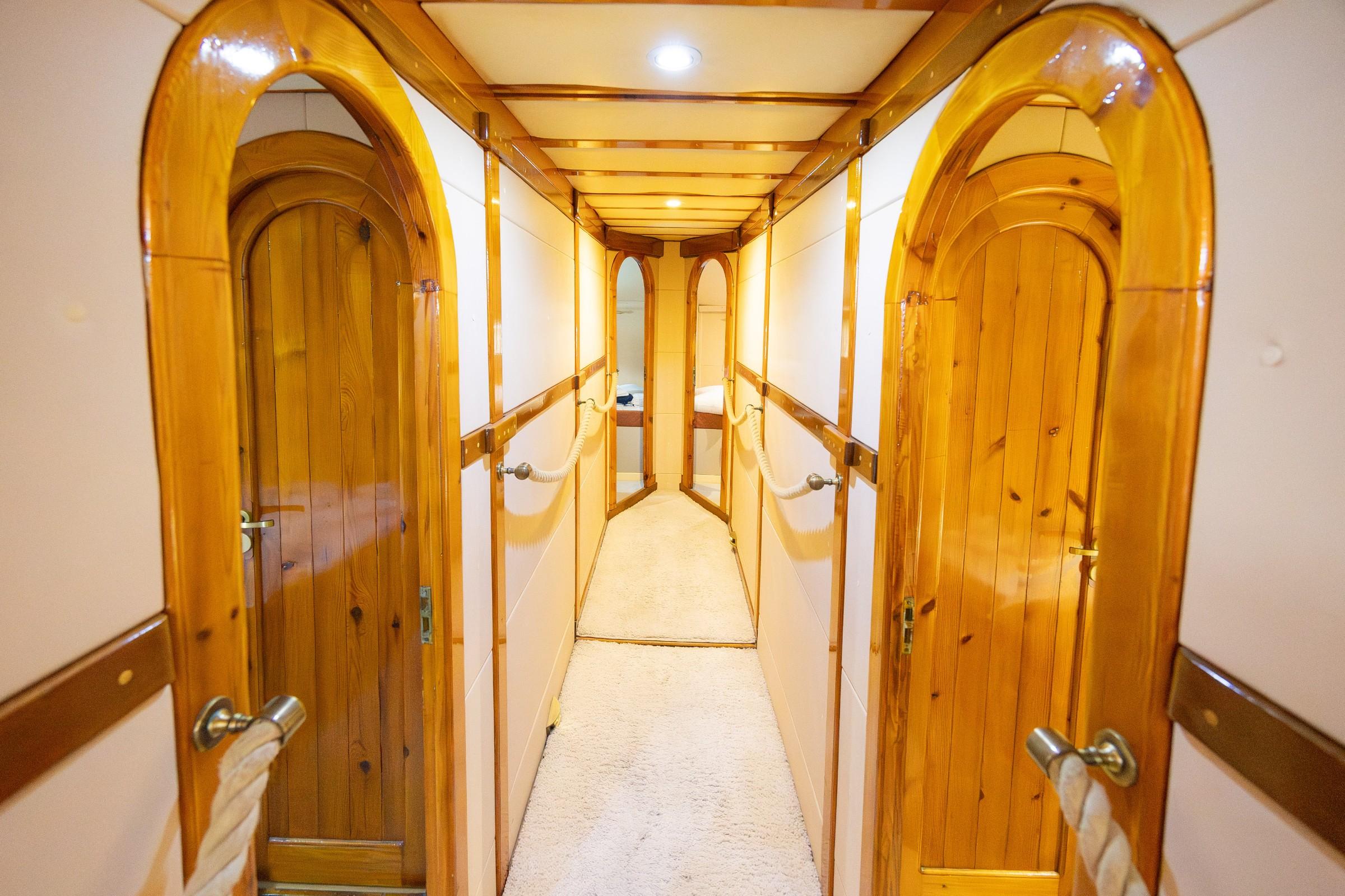 below deck passageway with varnished arched wooden cabin doors and cream carpet runner