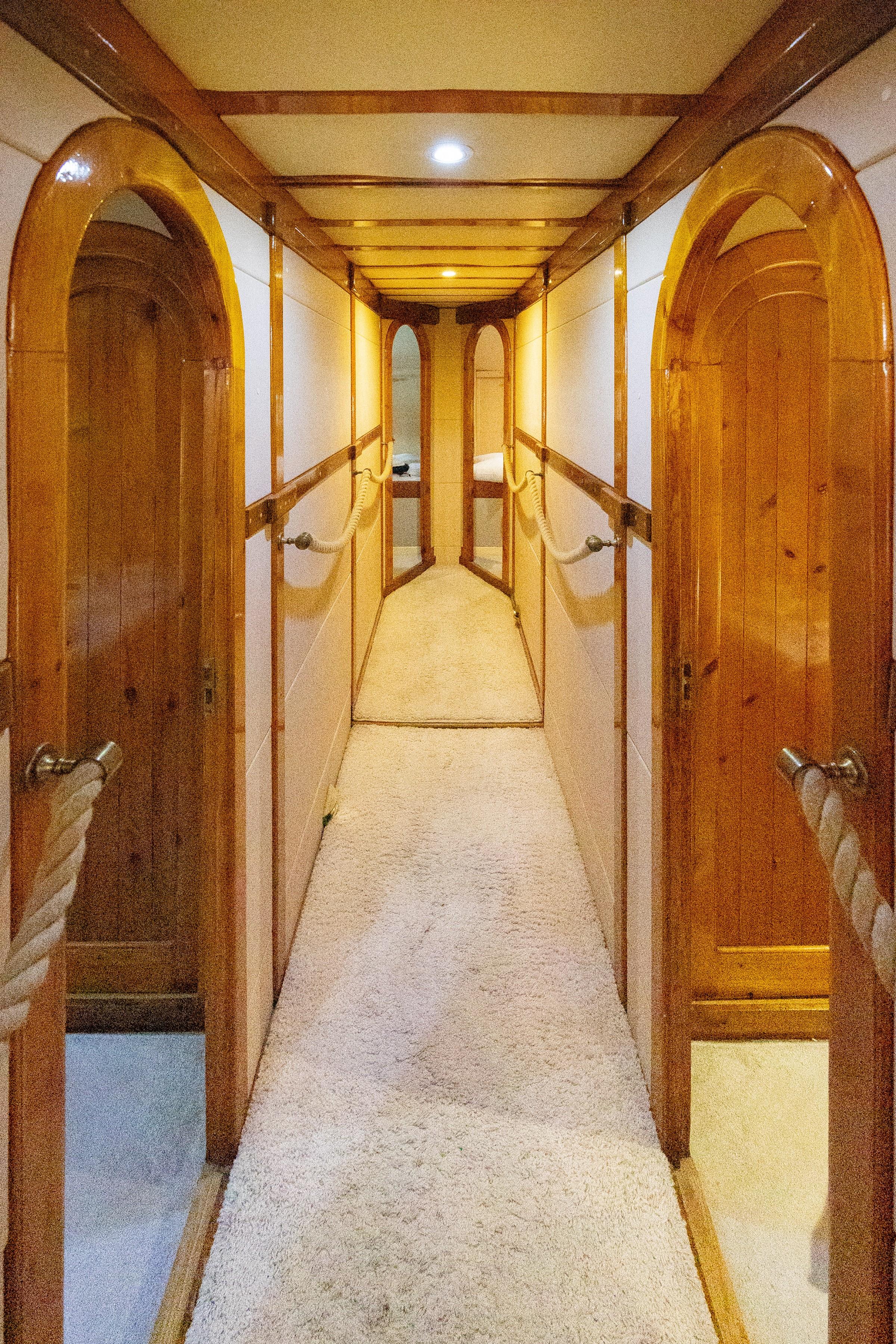 Gulet interior corridor with arched varnished timber cabin doors and rope handrails leading to cabin beyond