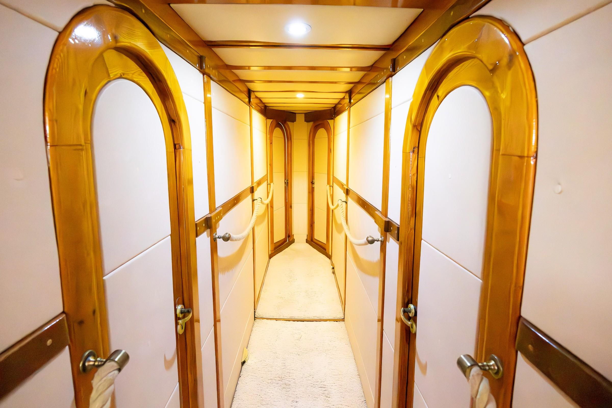 Below-deck passageway with polished wood arched doorframes leading to multiple guest cabin doors
