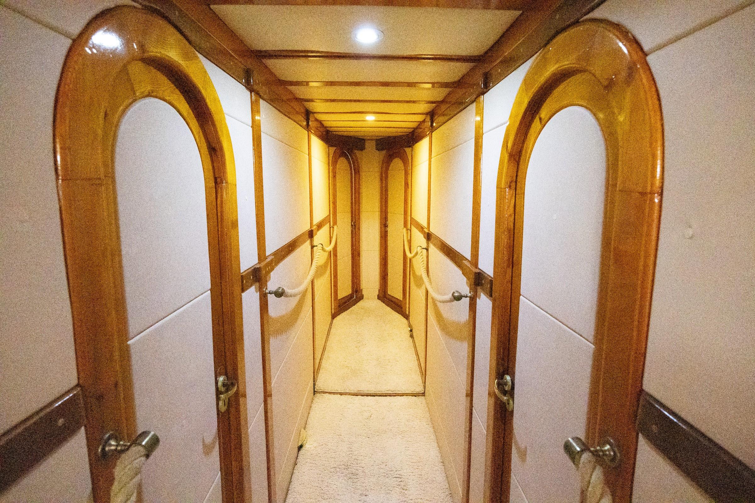 Below-deck passageway with polished teak arched doorframes leading to multiple guest cabin doors