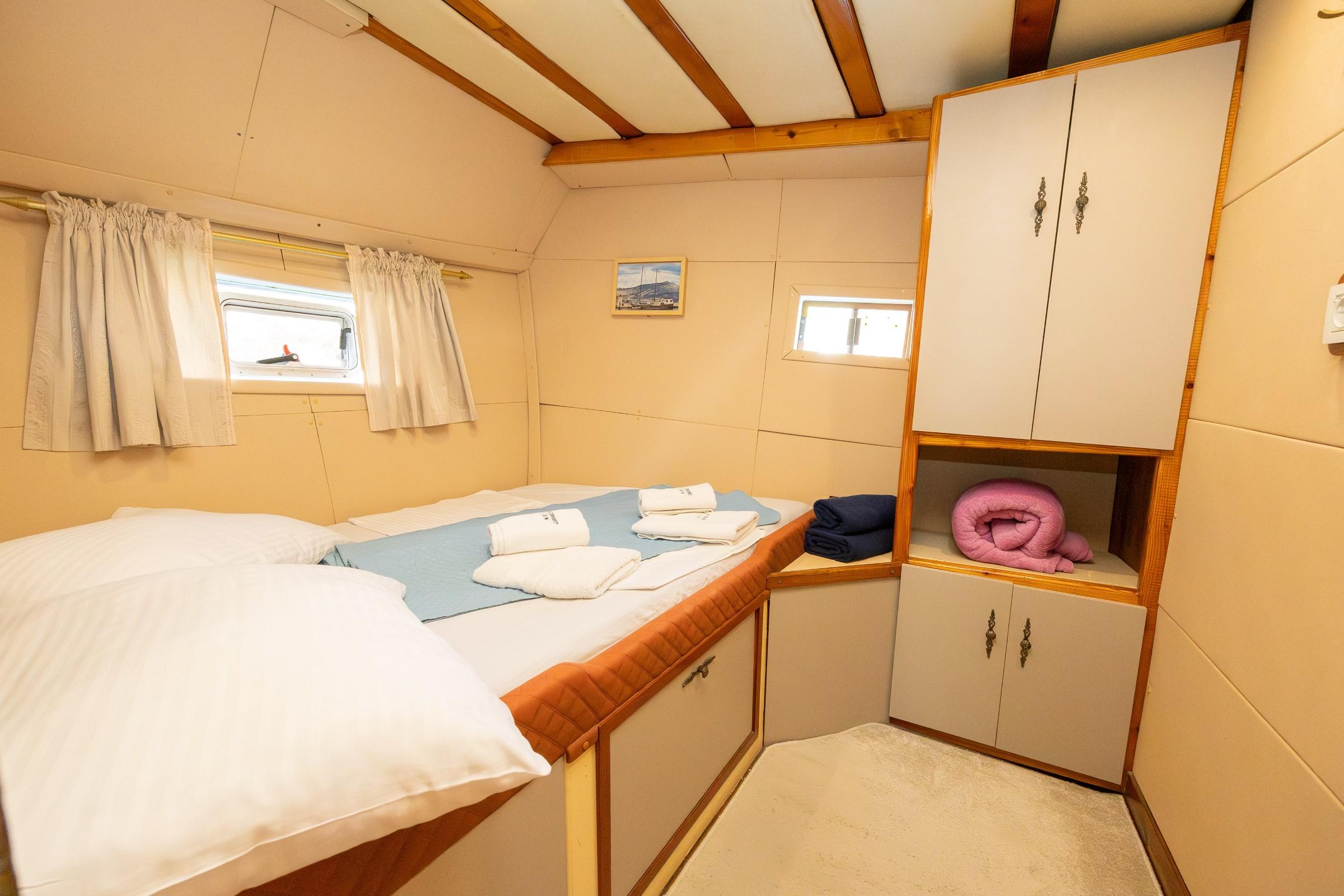 Gulet twin cabin with two single beds, folded white towels, and built-in cream cabinetry