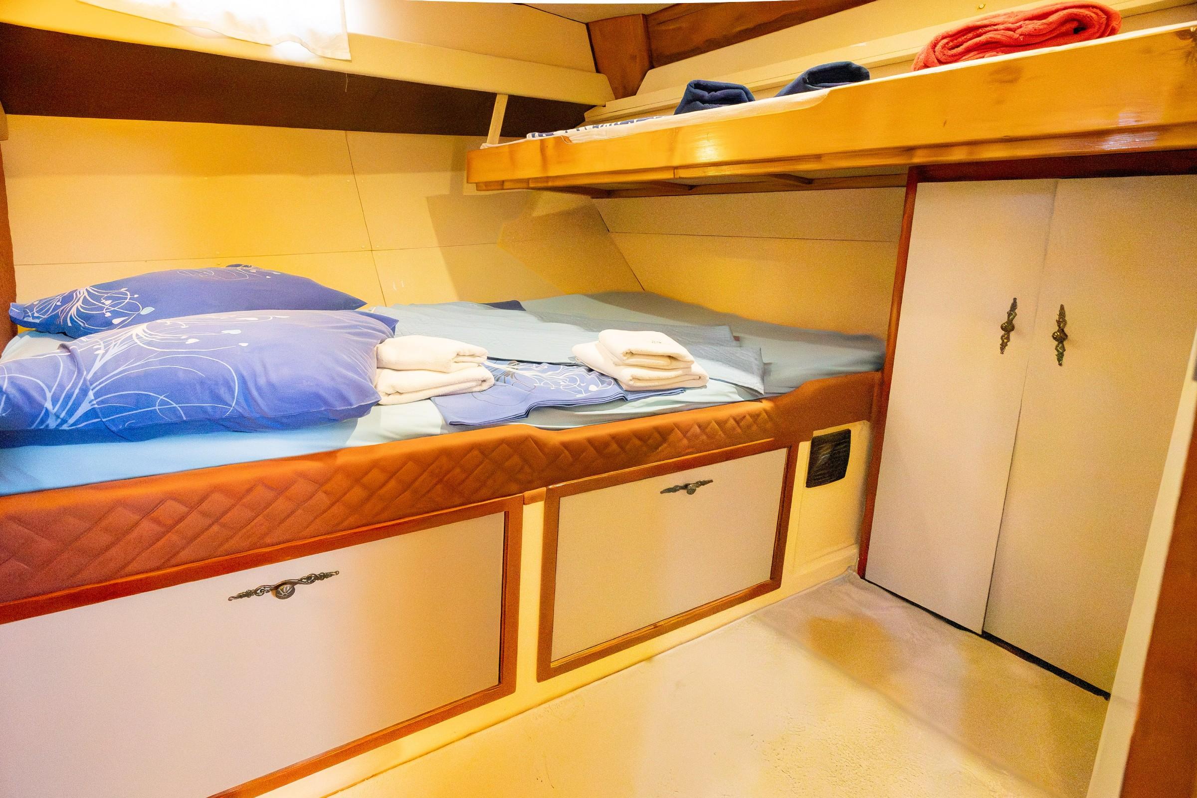 gulet twin cabin with bunk berths, blue bedding, folded towels and built-in wardrobe