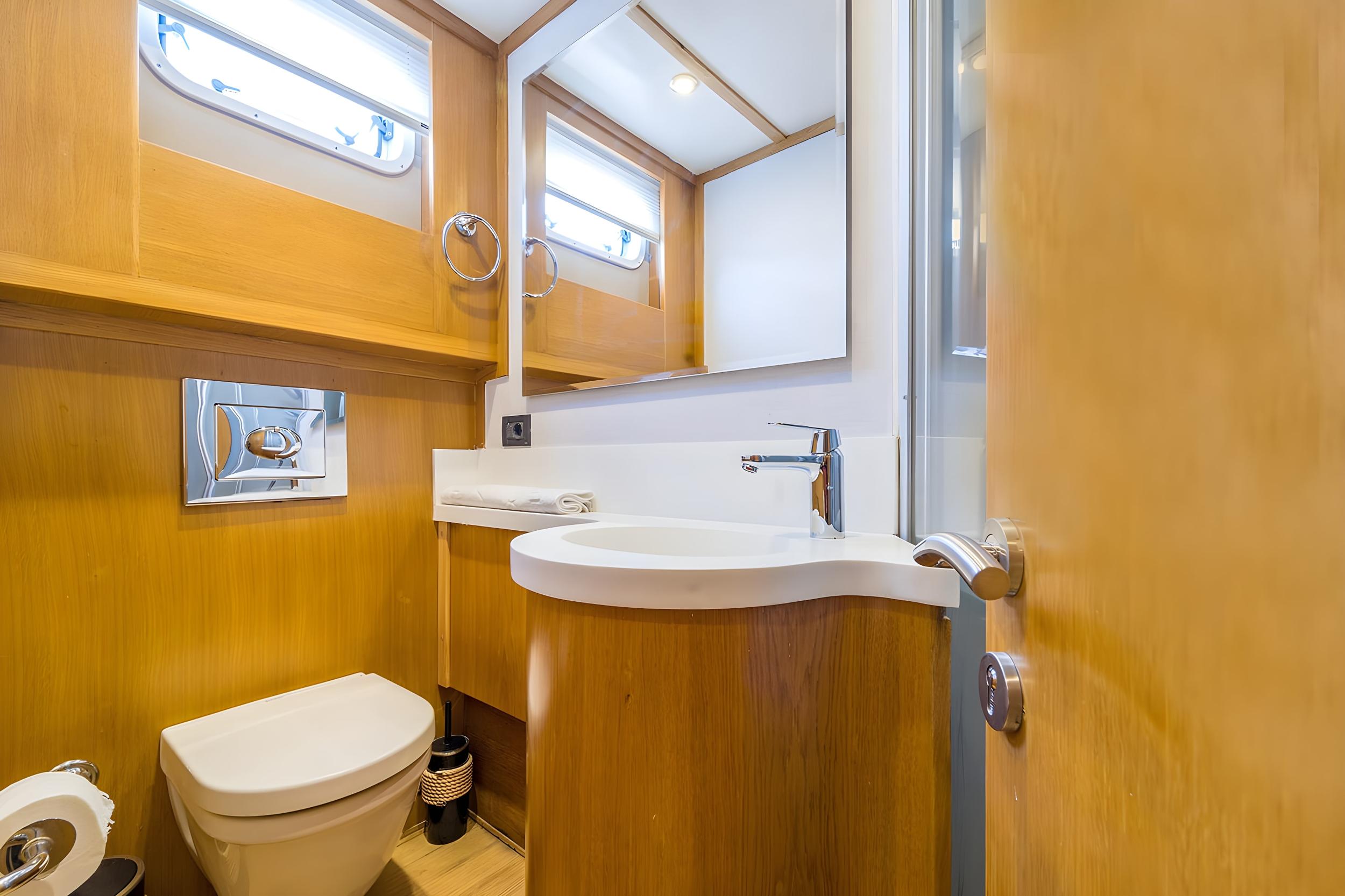 Yacht en-suite bathroom with wall-hung toilet, curved vanity basin, chrome tap, and large mirror