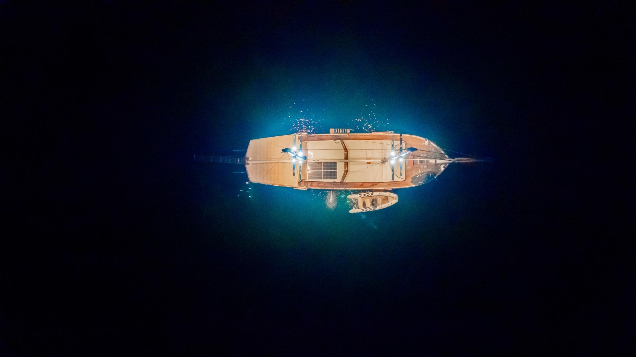 aerial night view of illuminated luxury yacht anchored in deep blue waters