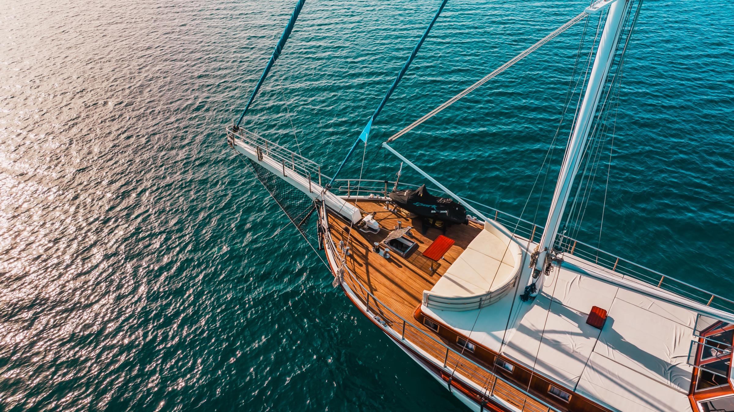 aerial drone shot of traditional wooden gulet with white hull sailing on crystal clear turquoise Mediterranean waters