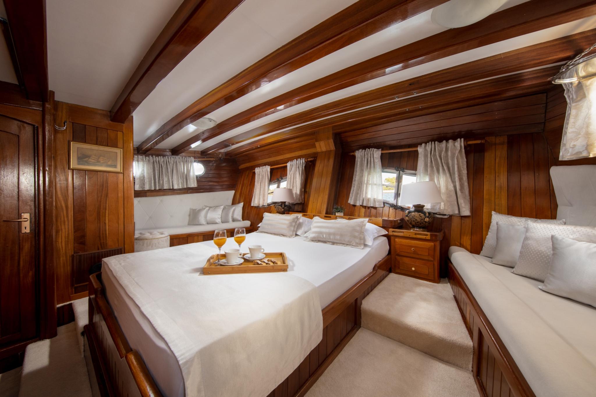 master cabin with double bed, wooden beams, portholes, and built-in seating