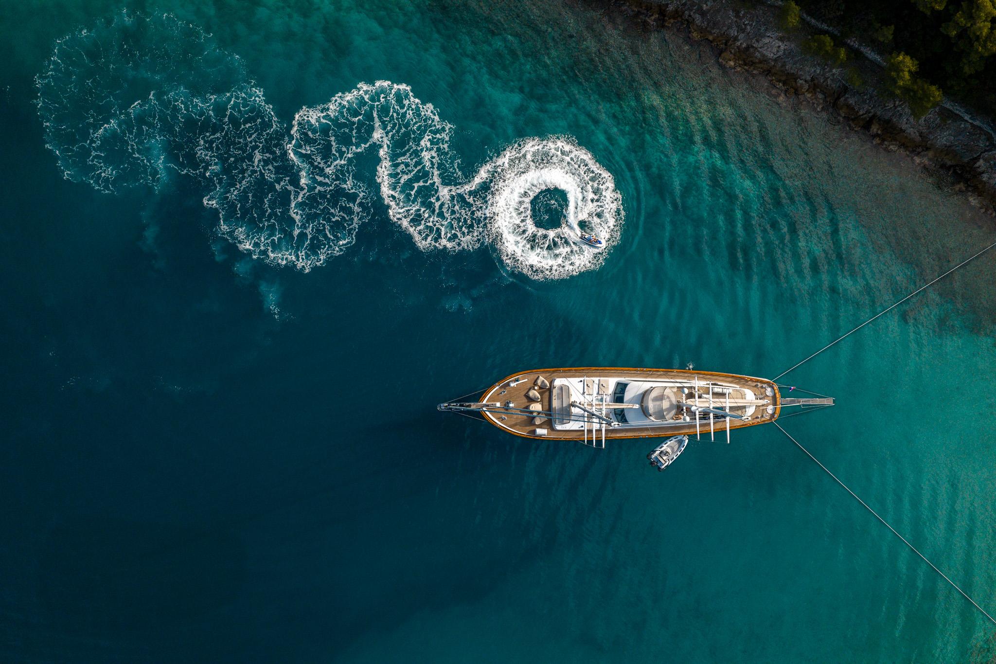 aerial view of traditional wooden gulet yacht anchored in crystal clear turquoise Mediterranean waters