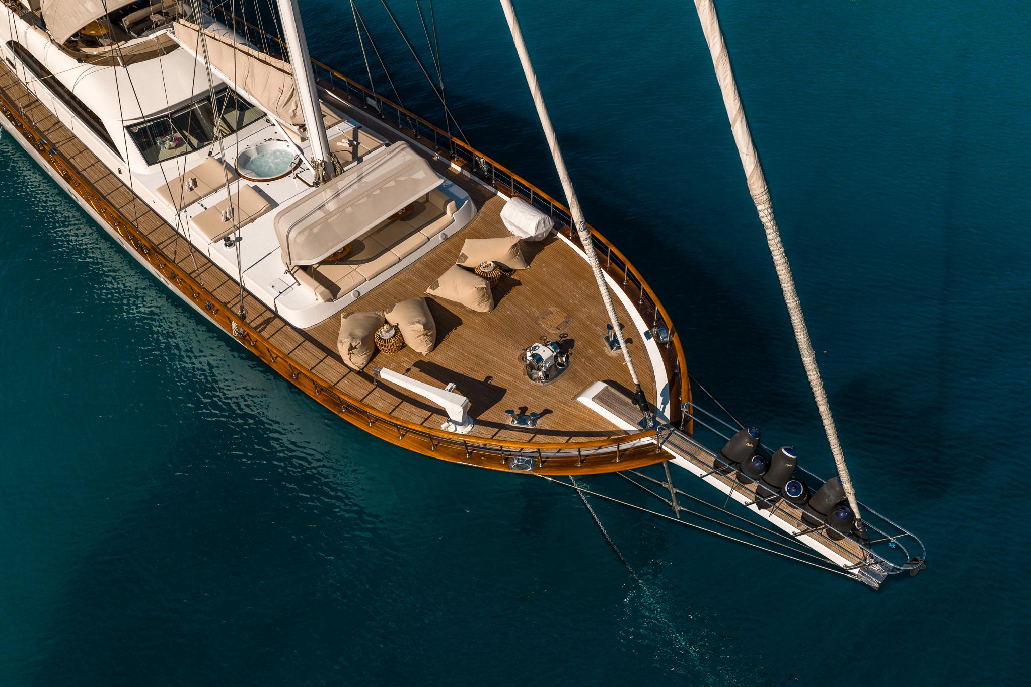 aerial drone shot of luxury sailing yacht with teak decks and jacuzzi anchored in turquoise waters