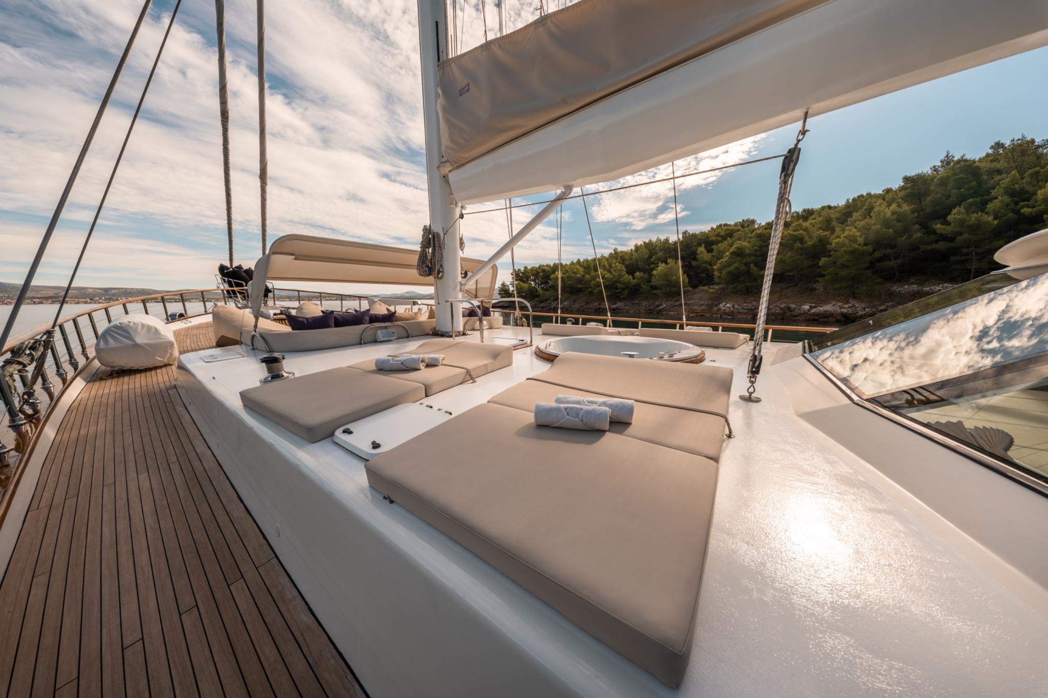 gulet bow deck with beige cushioned sunbeds and white canvas awning at sunset