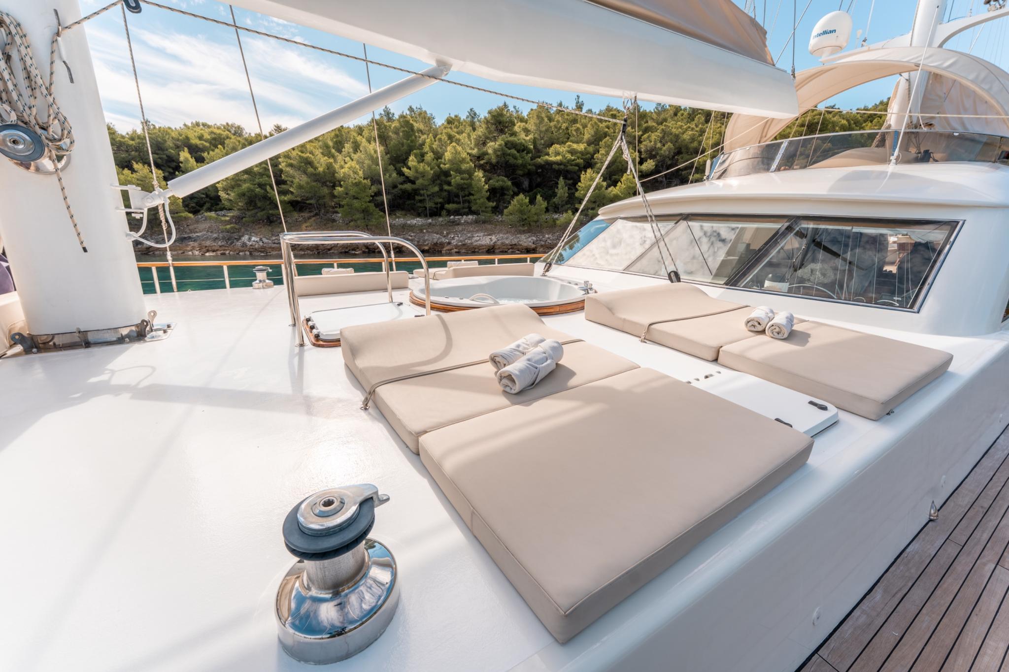 bow sun deck with beige cushioned loungers, canvas awning, and stainless steel rigging