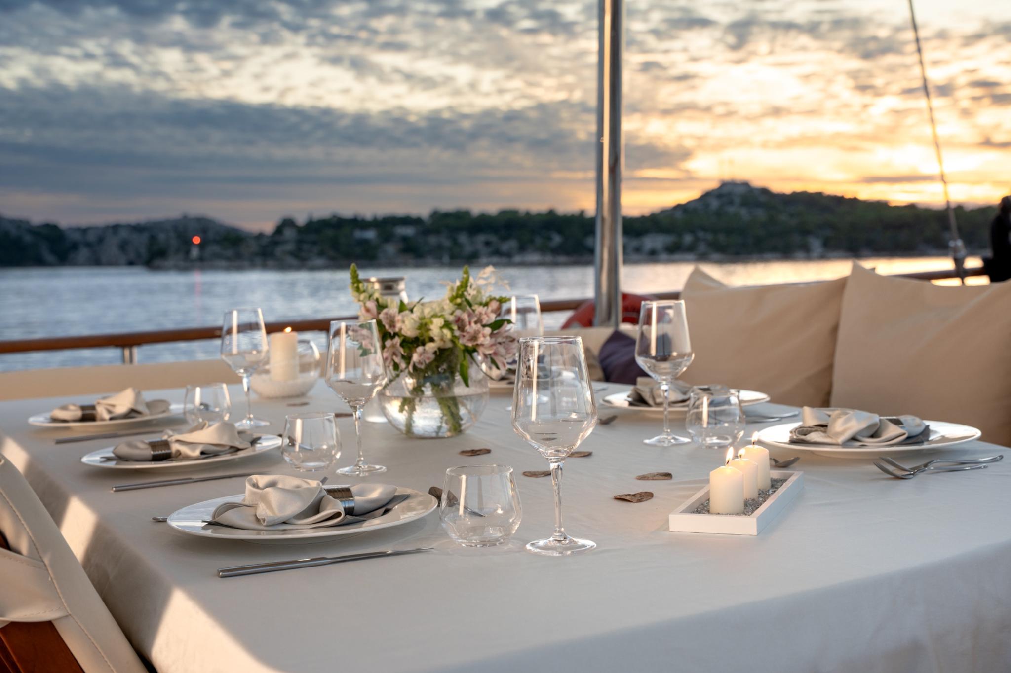 elegant dinner table setting with wine glasses candles and floral centerpiece at sunset
