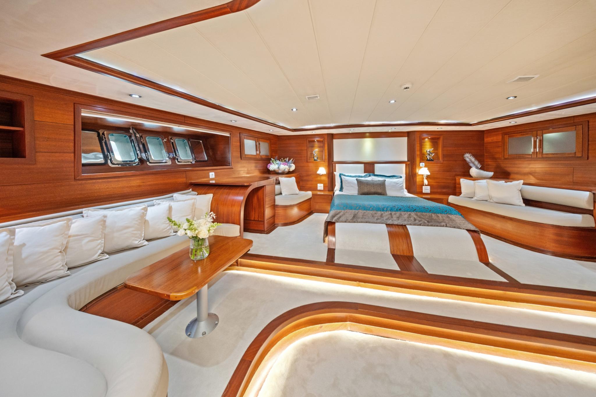 yacht cabin interior with double bed, white seating area, and rich wood paneling