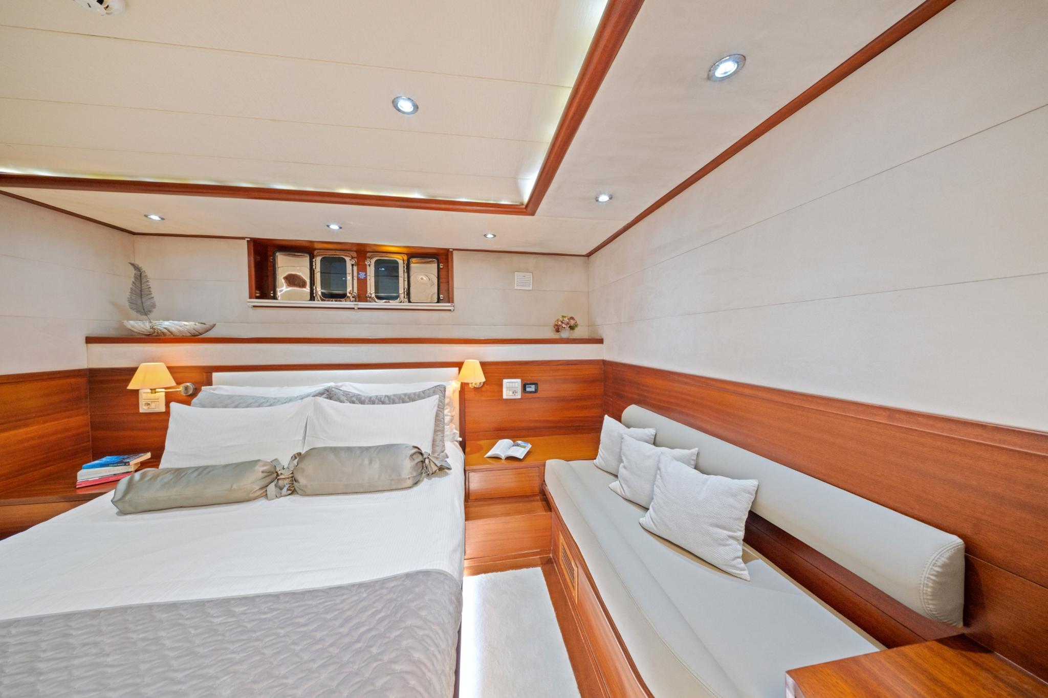yacht twin cabin with double bed, single berth, wood paneling and portholes