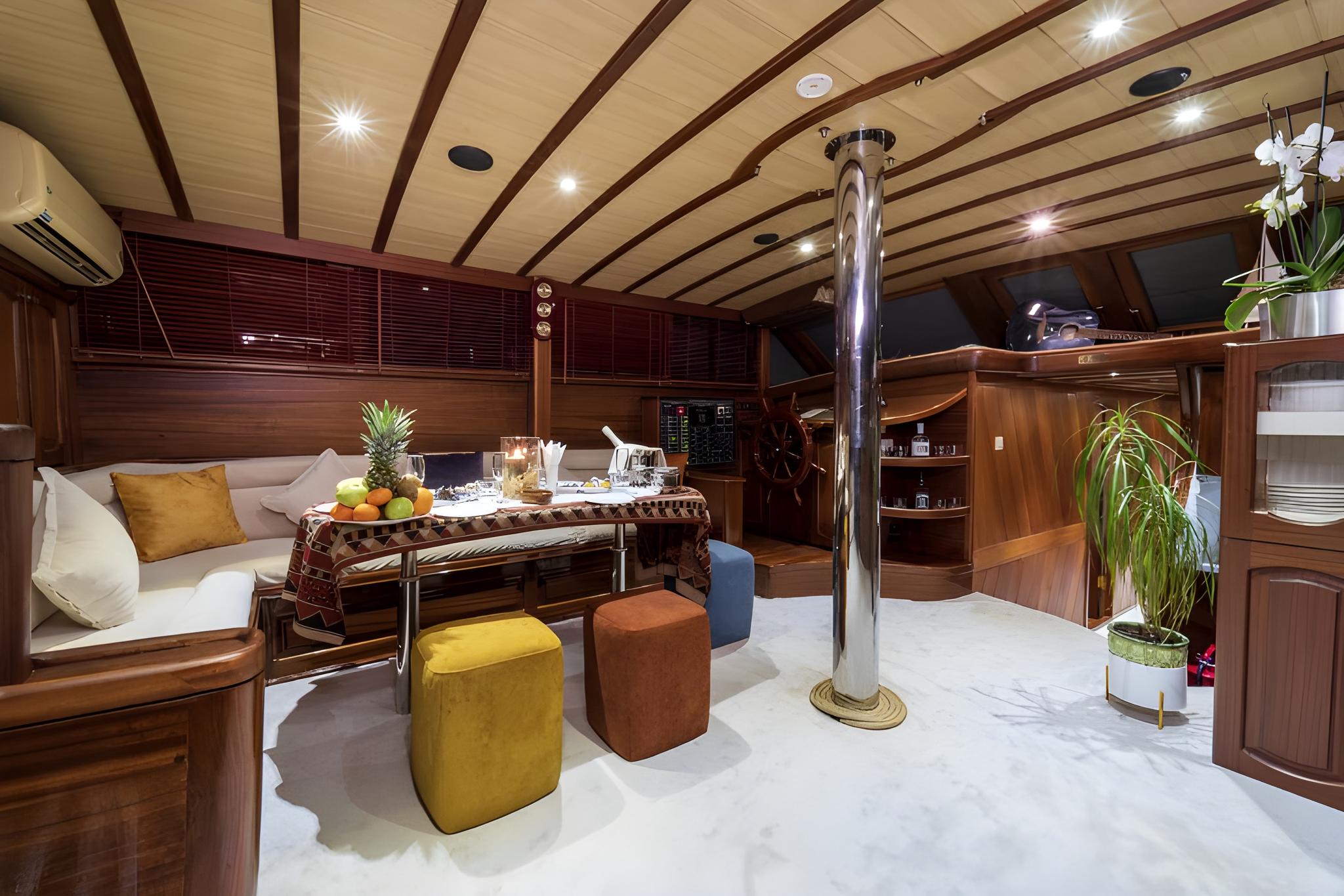 yacht interior salon with curved seating, exposed wooden beams, chrome pole and ottoman seating