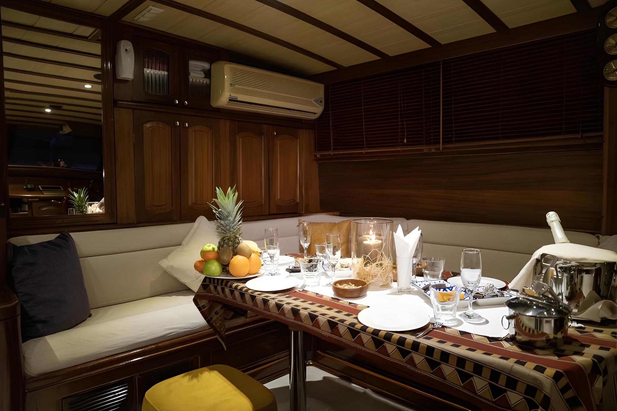 yacht interior dining area with served meal, wine glasses, fruit bowl and table setting