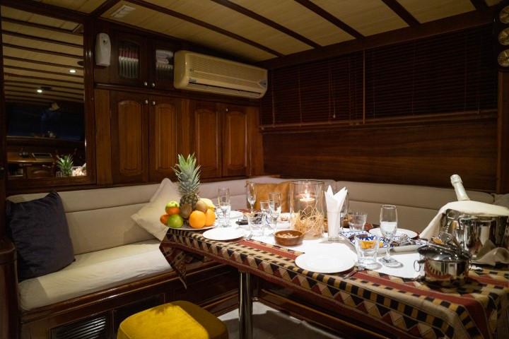 yacht interior dining area with served meal, wine glasses, fruit bowl and table setting