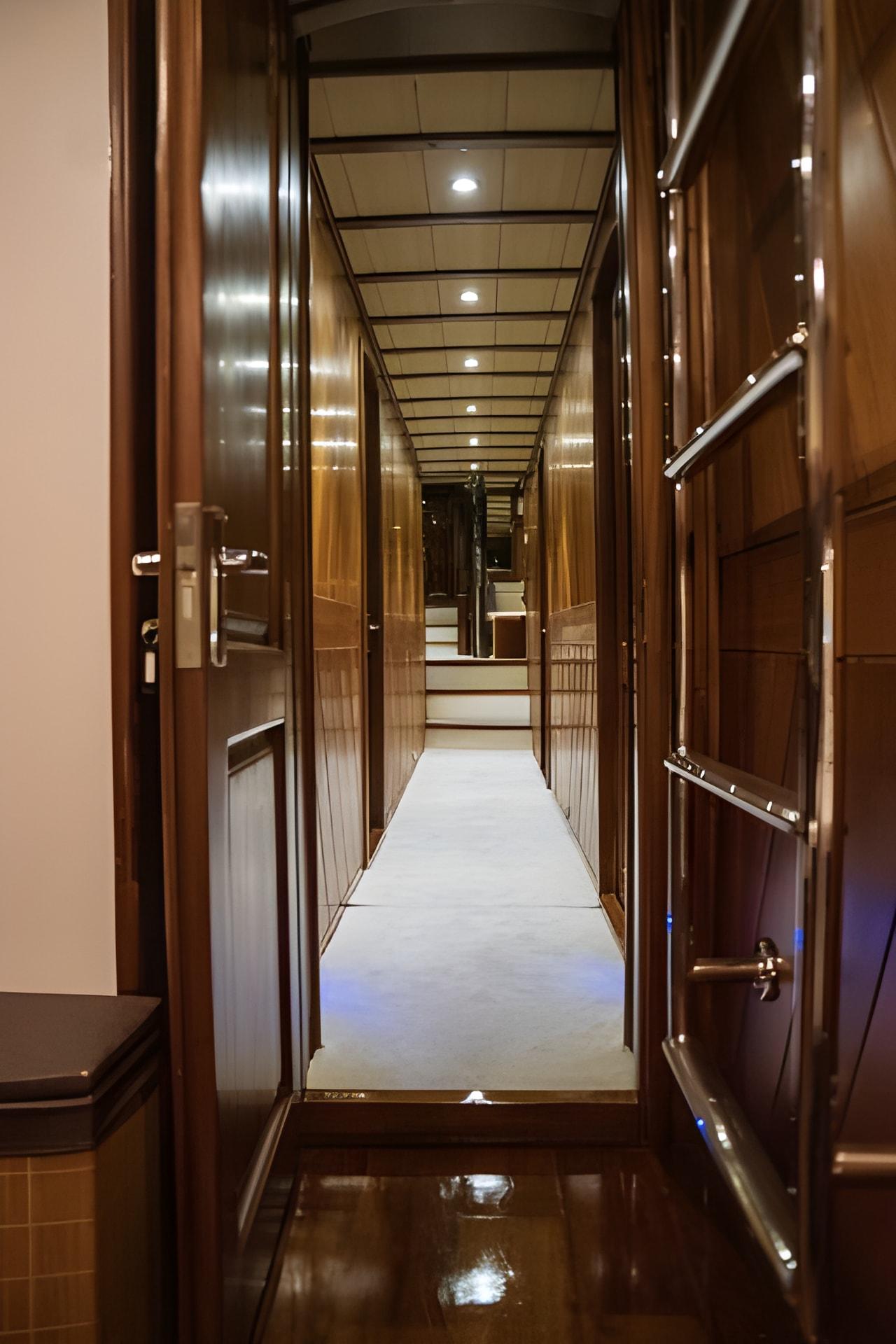 luxury yacht interior corridor with glossy wooden paneled walls and recessed ceiling lighting