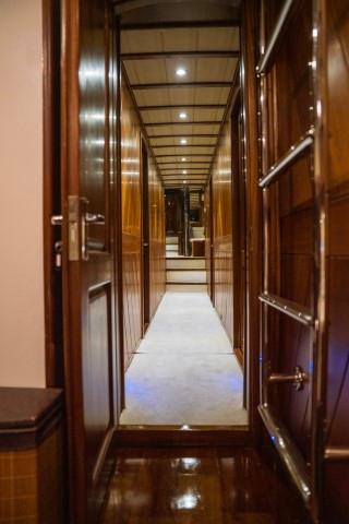 luxury yacht interior corridor with glossy wooden paneled walls and recessed ceiling lighting