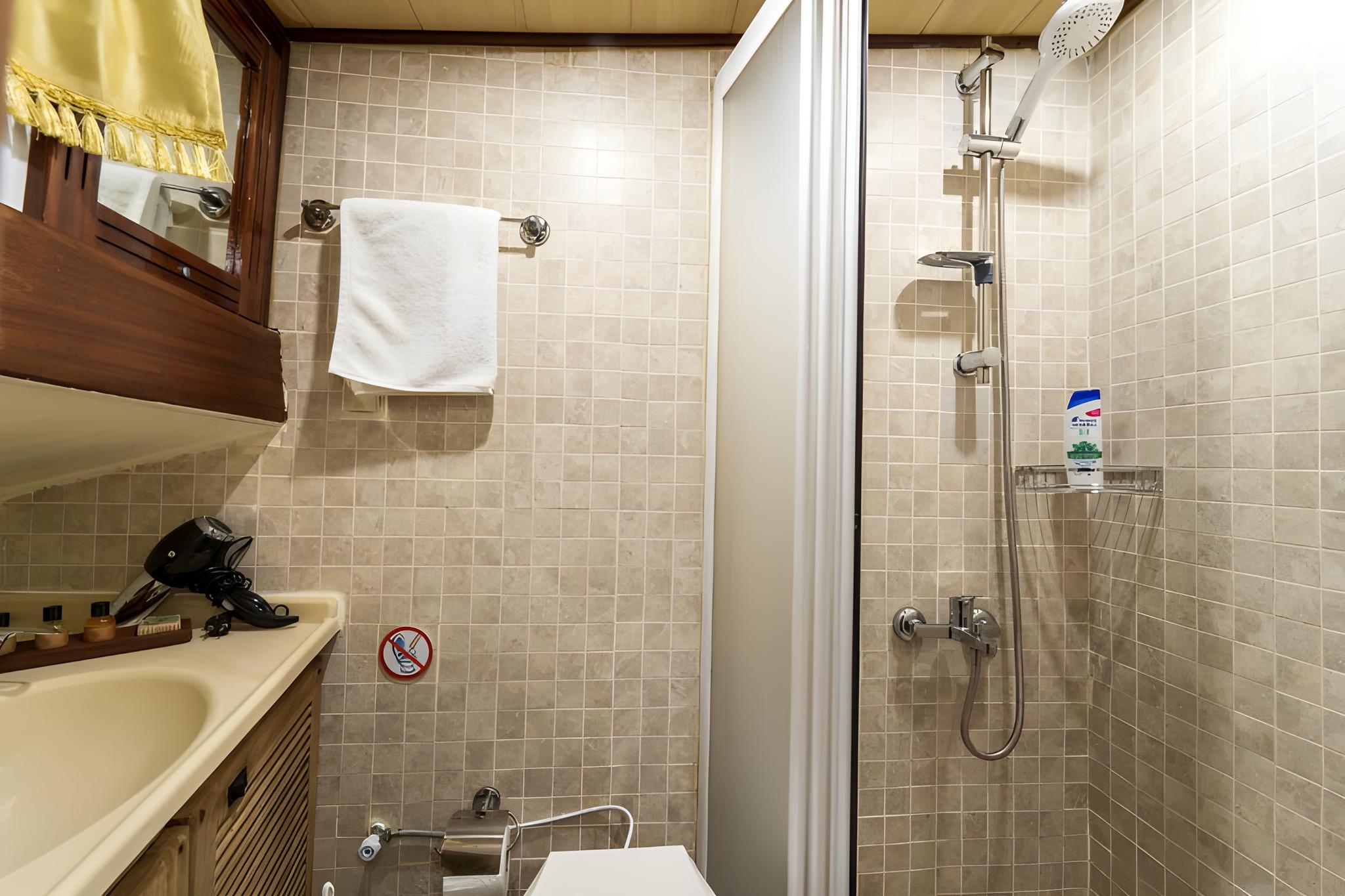yacht bathroom interior with tiled shower, vanity sink, mirror and toiletries