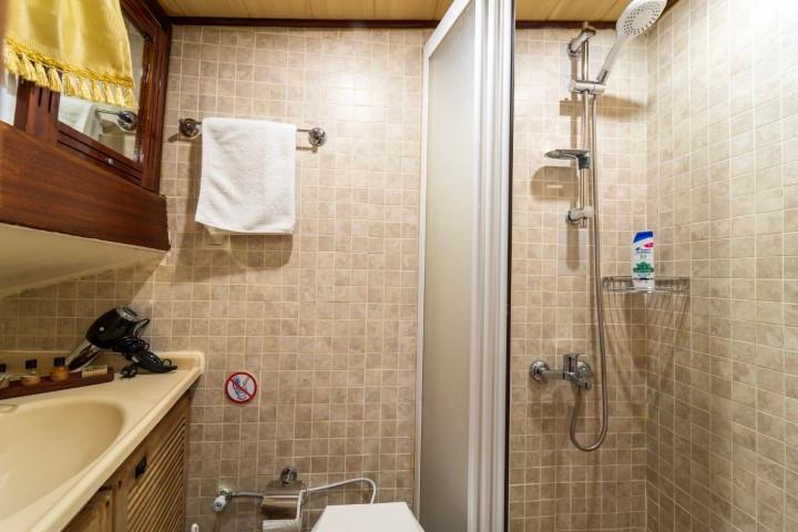 yacht bathroom interior with tiled shower, vanity sink, mirror and toiletries