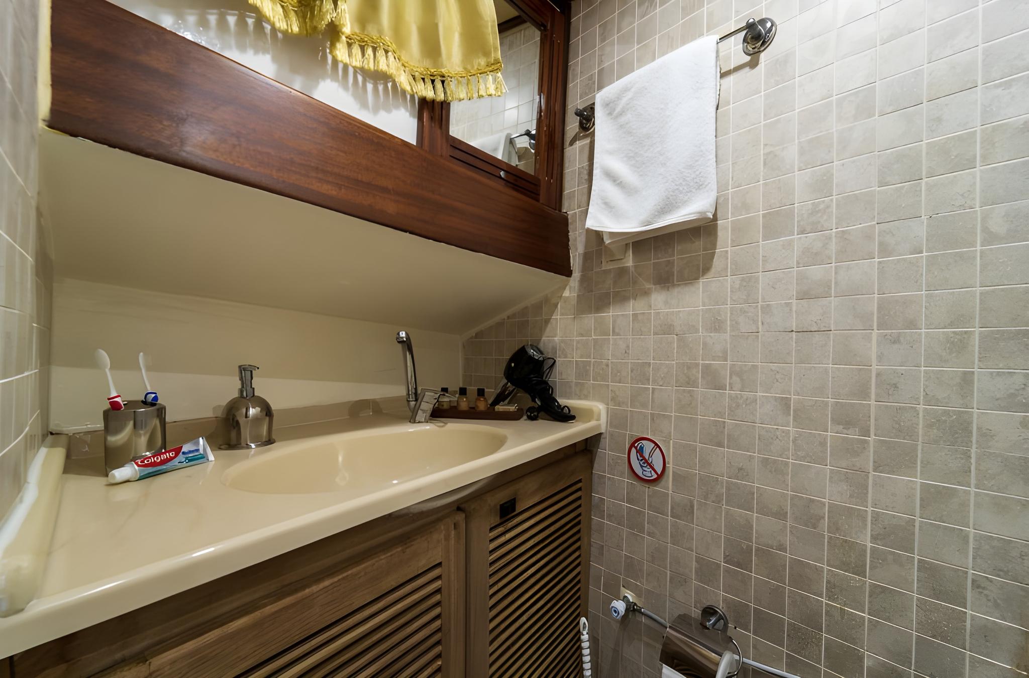 yacht bathroom featuring integrated sink, wooden mirror frame and beige tiled walls