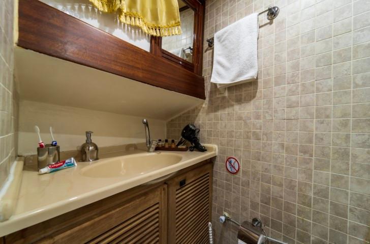 yacht bathroom featuring integrated sink, wooden mirror frame and beige tiled walls
