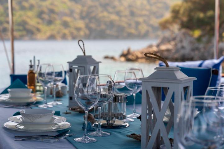 yacht dining table set with wine glasses, white lanterns and coastal backdrop