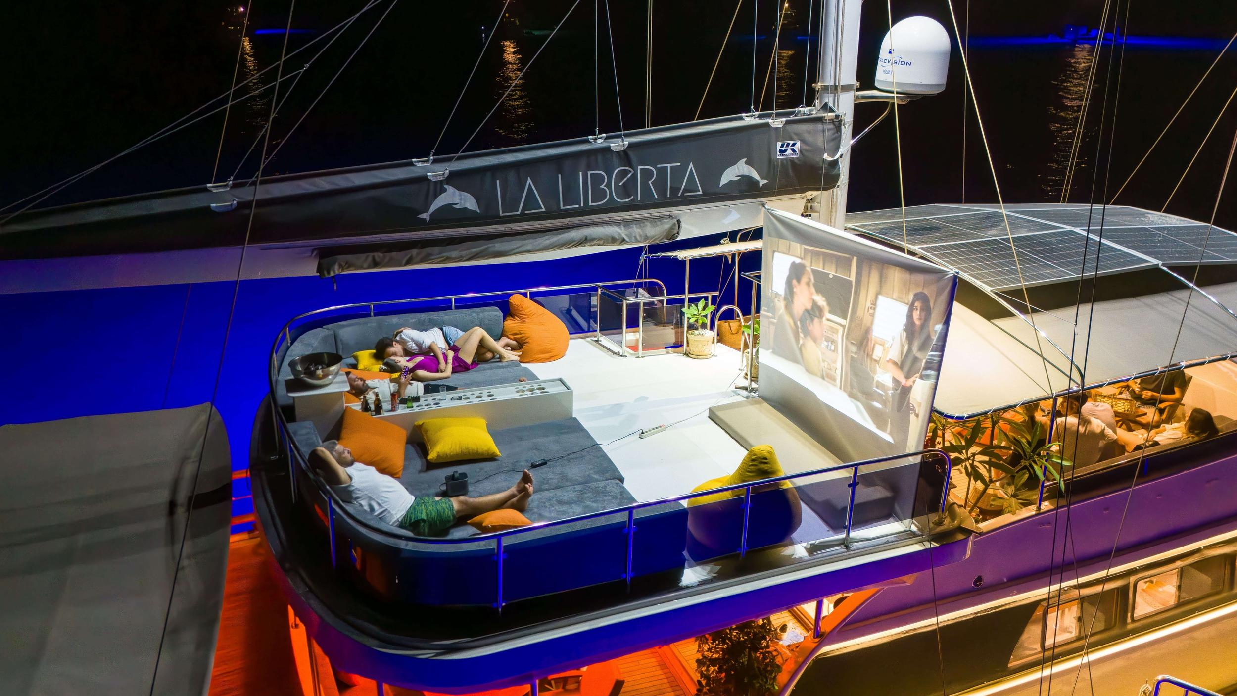 guests watching outdoor movie projection on La Liberta gulet sundeck at night with bean bags and cushioned seating