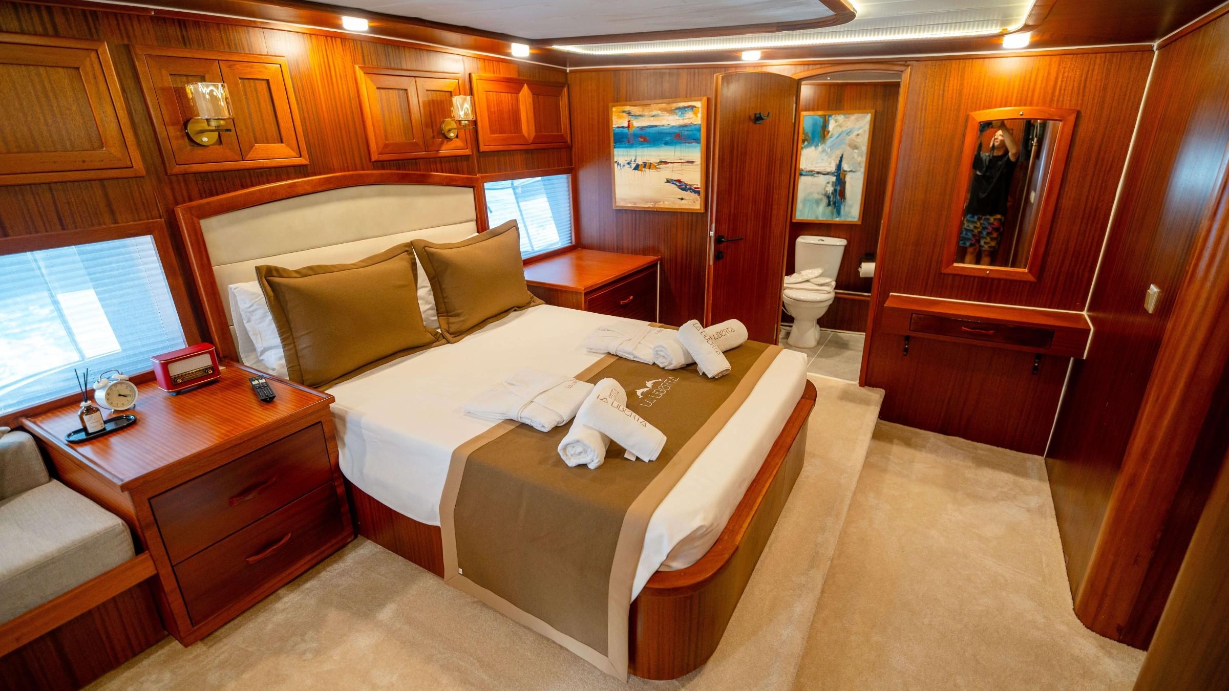 La Liberta gulet master cabin with king bed, branded towels, and open en-suite toilet visible