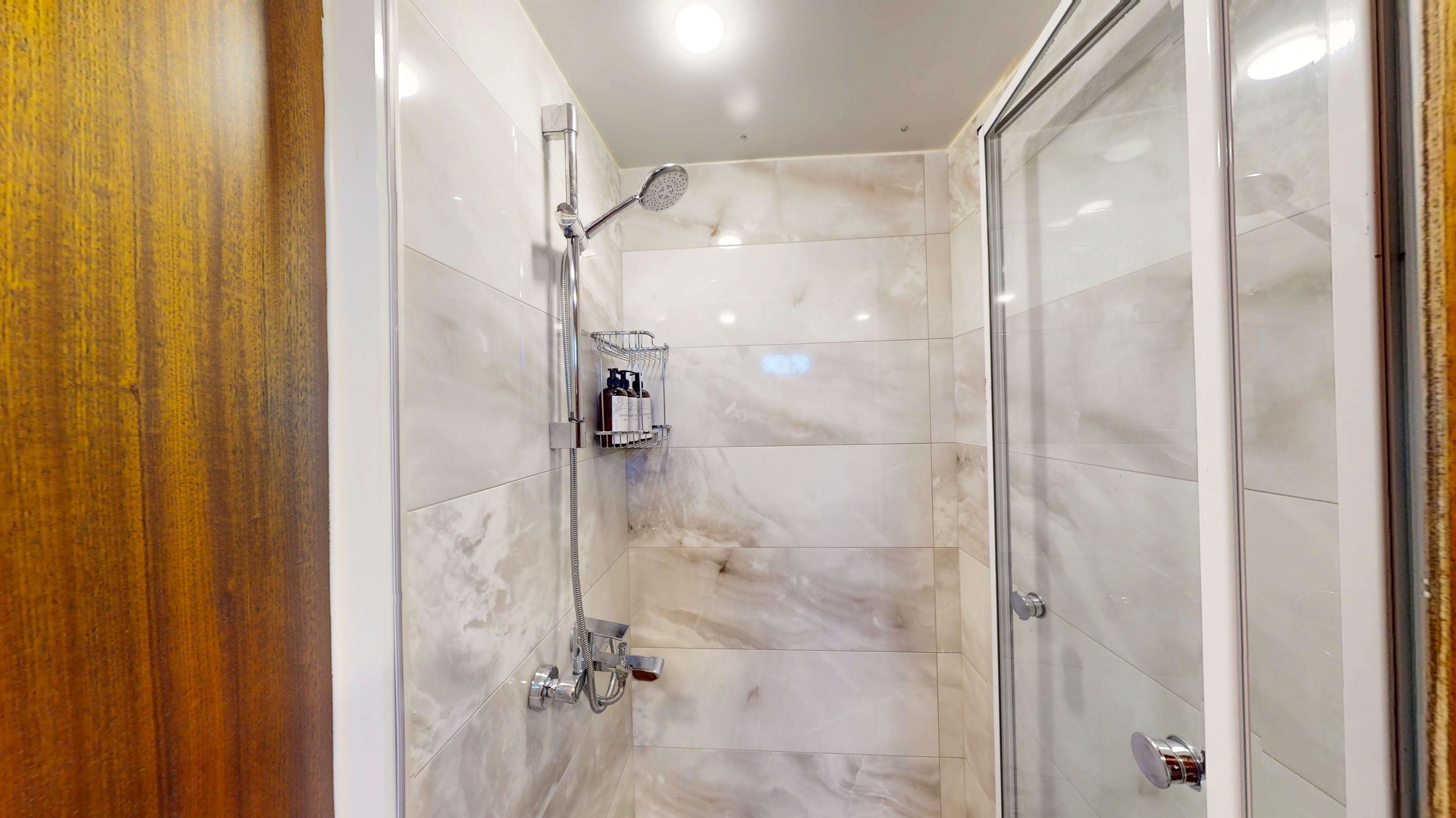 Luxury cabin en-suite shower with marble-effect tiles, chrome rail and handheld showerhead