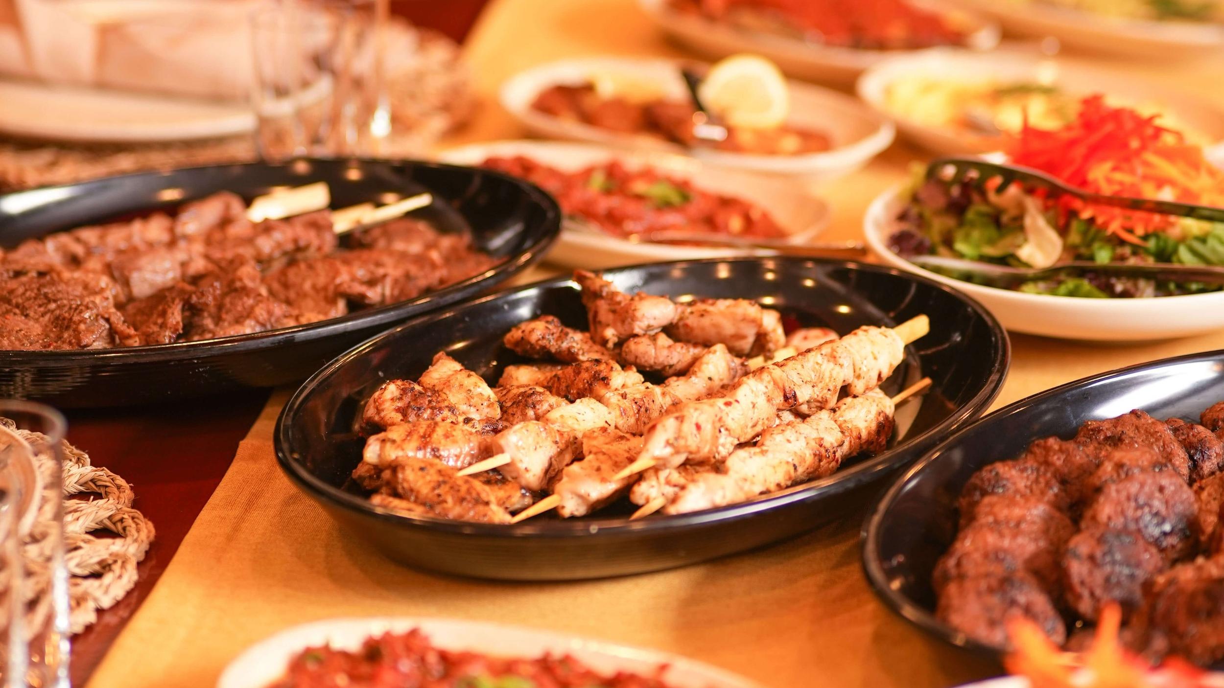 luxury gulet dining spread with chicken shish kebab skewers, grilled kofte and fresh salads served on black platters