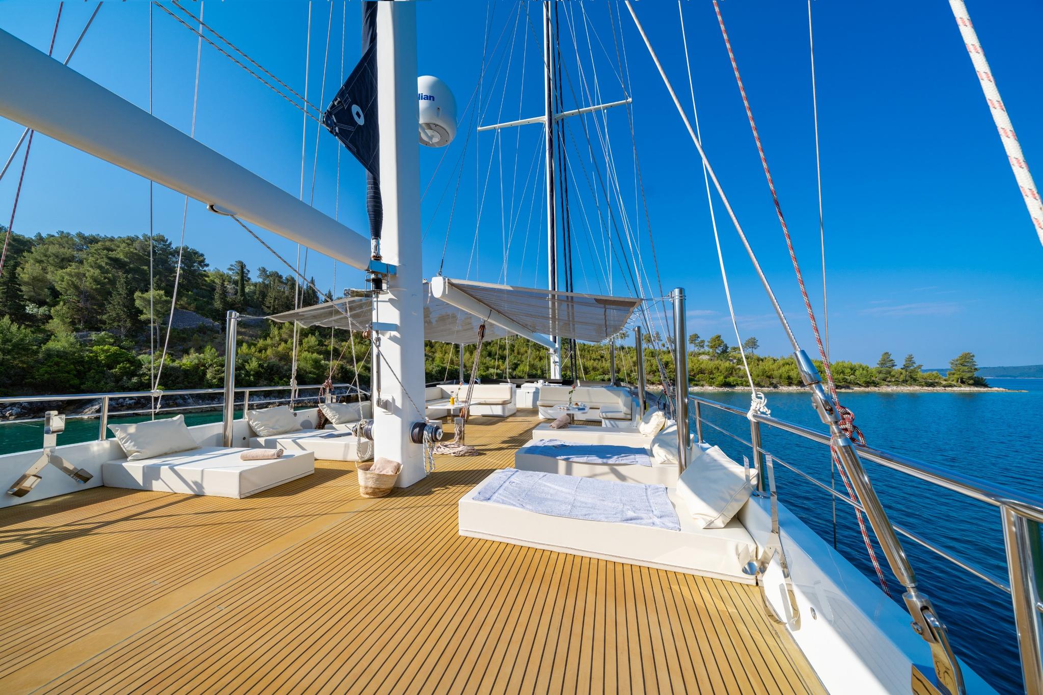 luxury gulet foredeck with white cushioned seating areas and teak decking