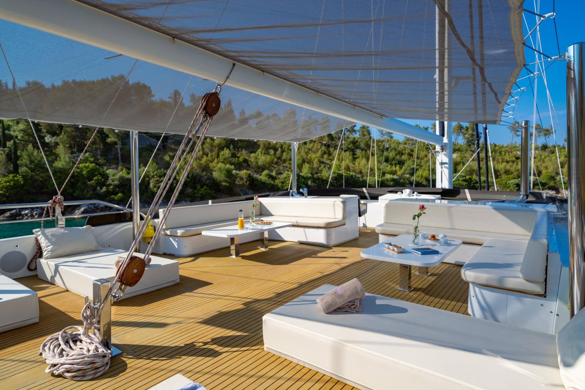 gulet upper deck lounge with white cushioned seating, teak decking, and canvas awning overhead