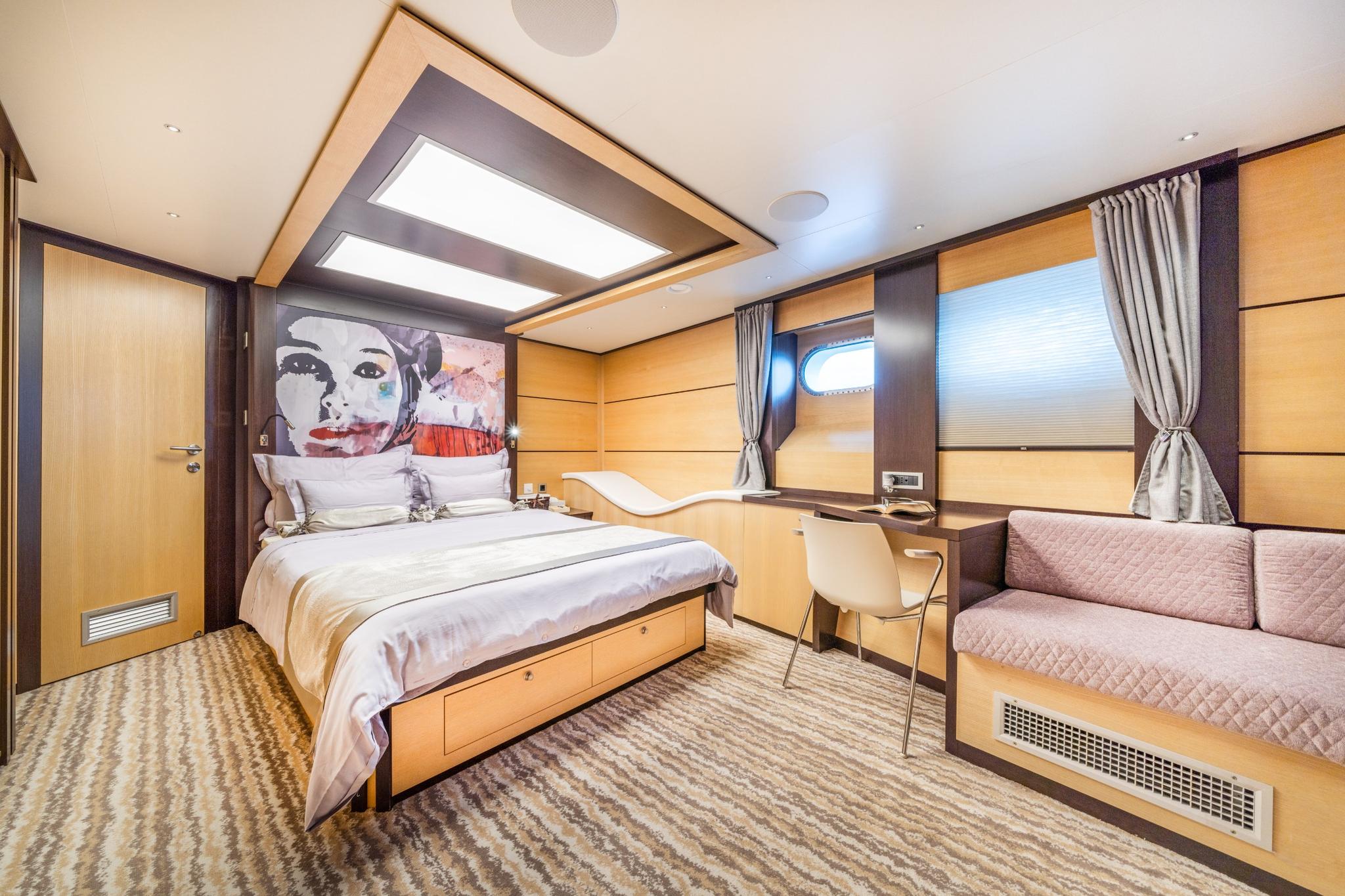 yacht guest cabin featuring double bed with pop art headboard and built-in sofa seating