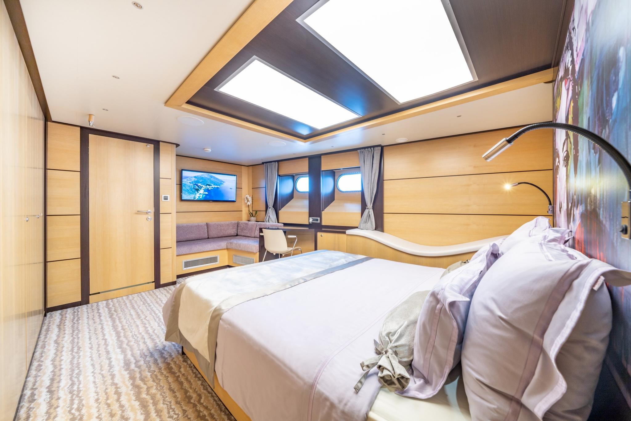 Master cabin with king size bed, panoramic windows, seating area and wall-mounted television
