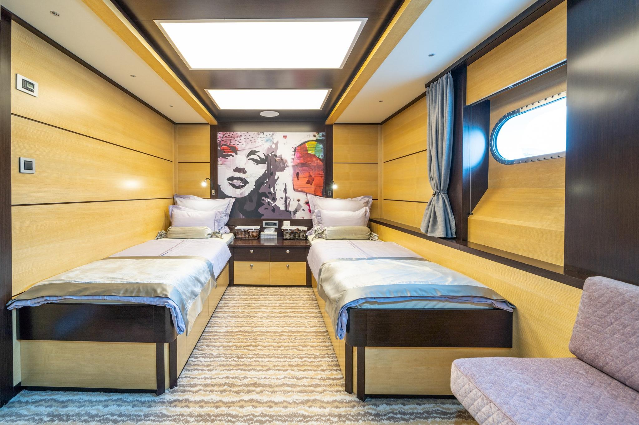 yacht guest cabin featuring twin beds, contemporary artwork, porthole window and neutral decor