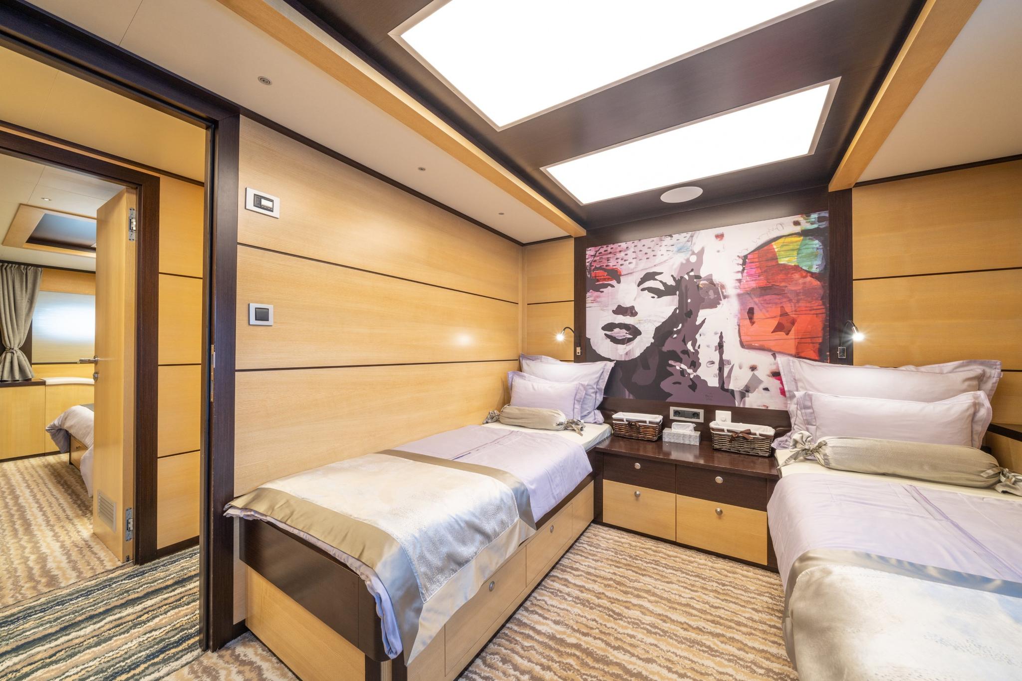 yacht guest cabin with two single beds, colorful Marilyn Monroe pop art headboard and skylights