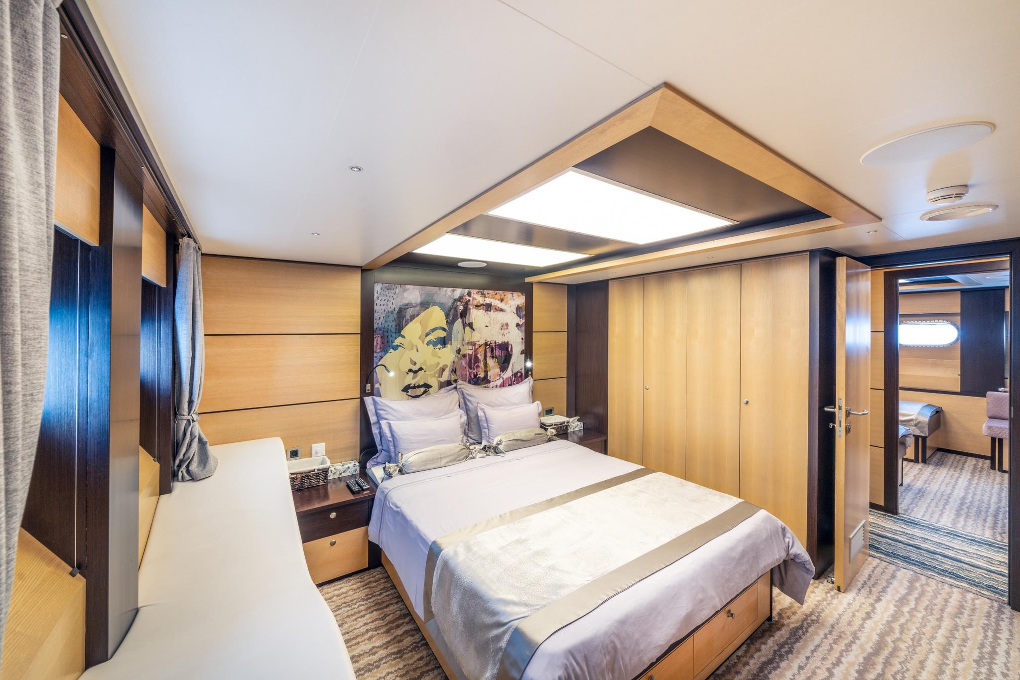 yacht cabin interior with double bed, pop art headboard, built-in wardrobes and porthole windows