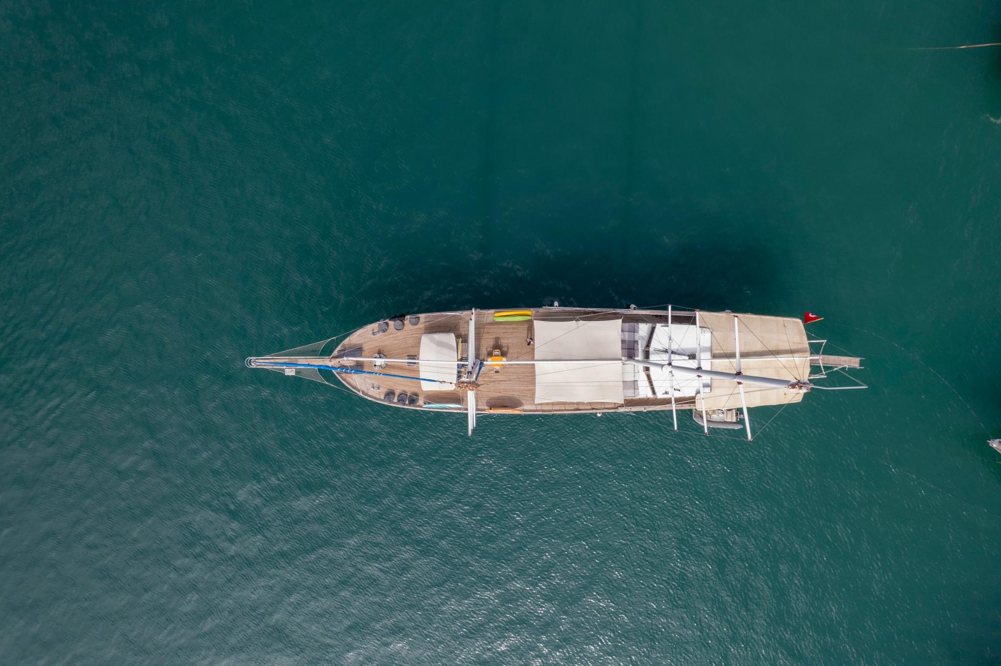 aerial view of traditional gulet yacht with white hull anchored in clear turquoise waters