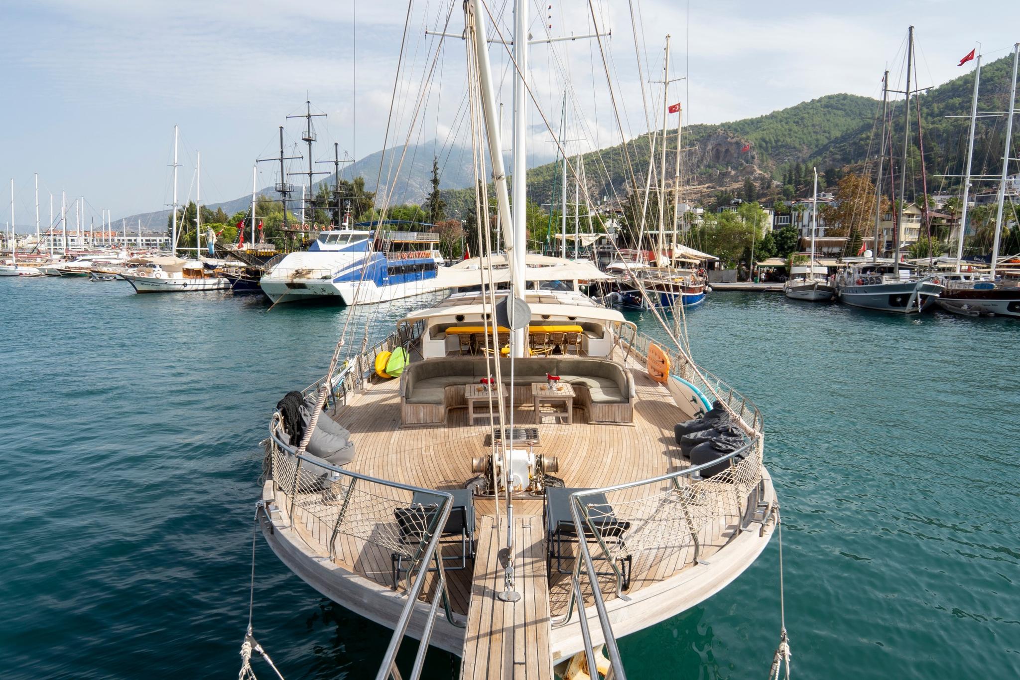 traditional gulet bow deck with curved seating area and sailing rigging moored at Mediterranean marina