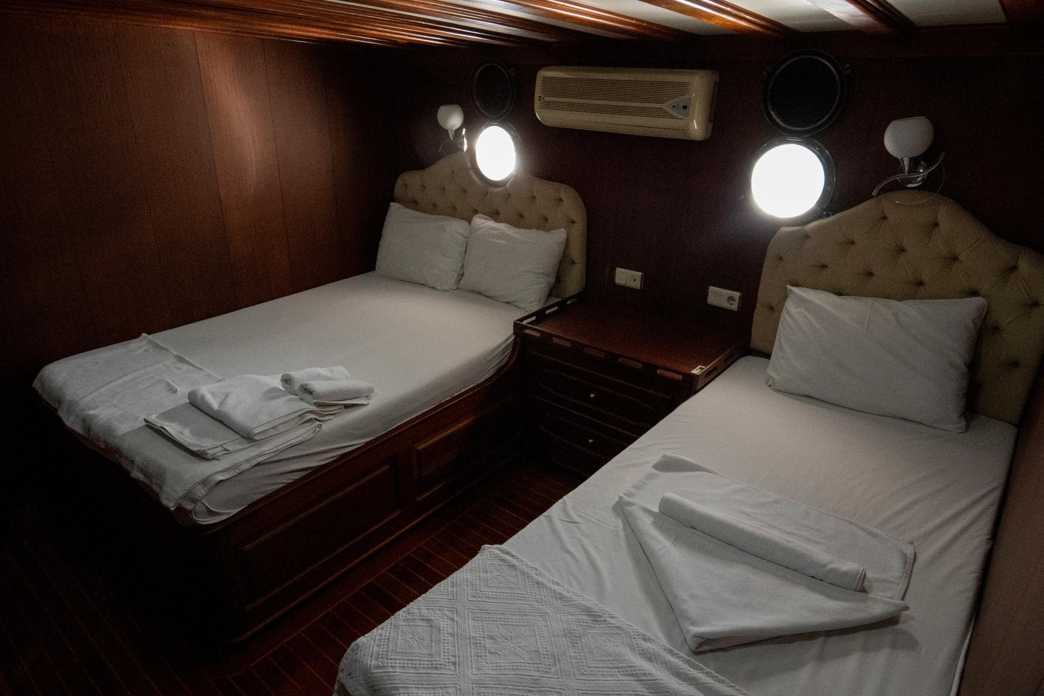yacht twin cabin with two single beds, beige tufted headboards and white linens