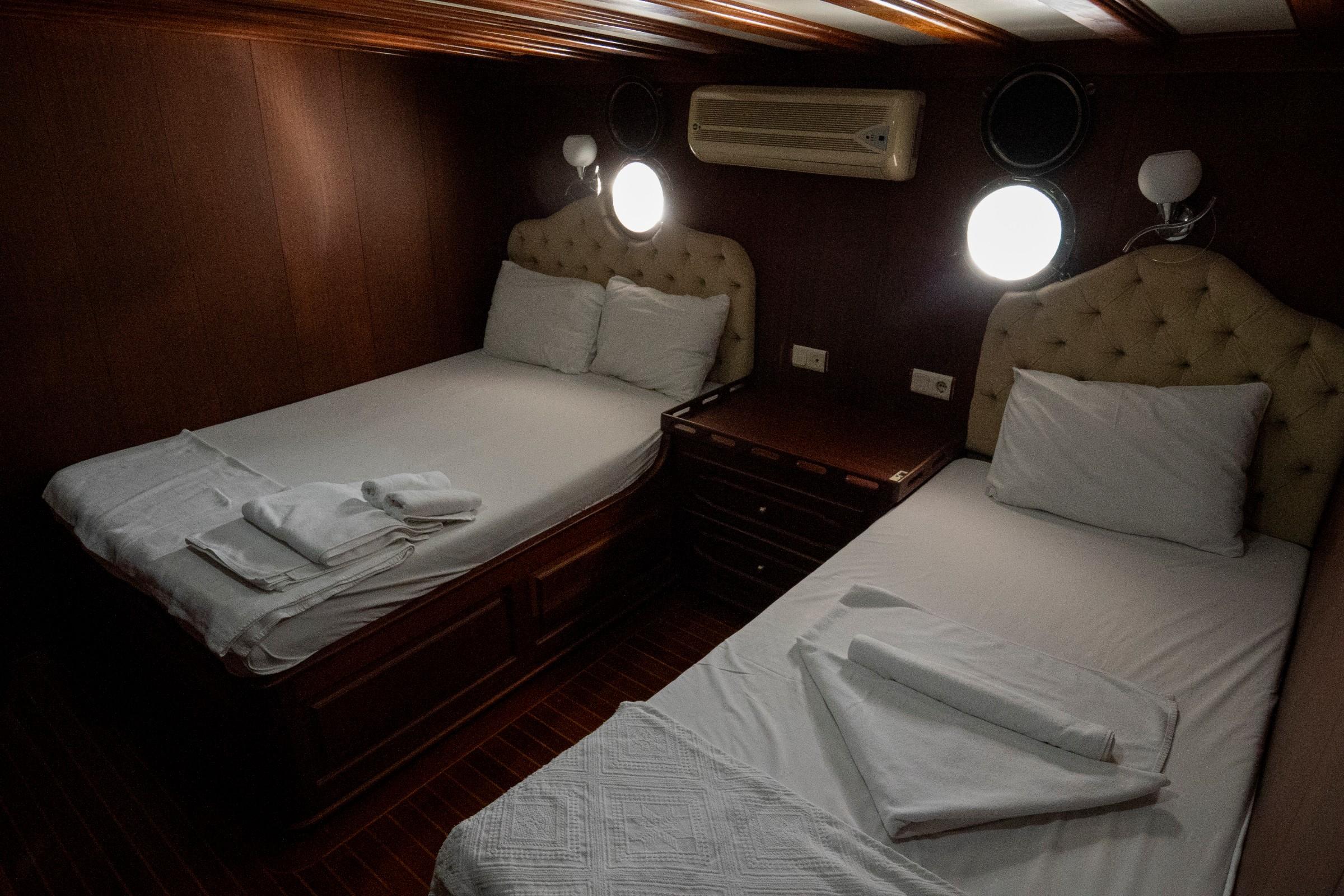 yacht twin cabin with two single beds, beige tufted headboards and white linens