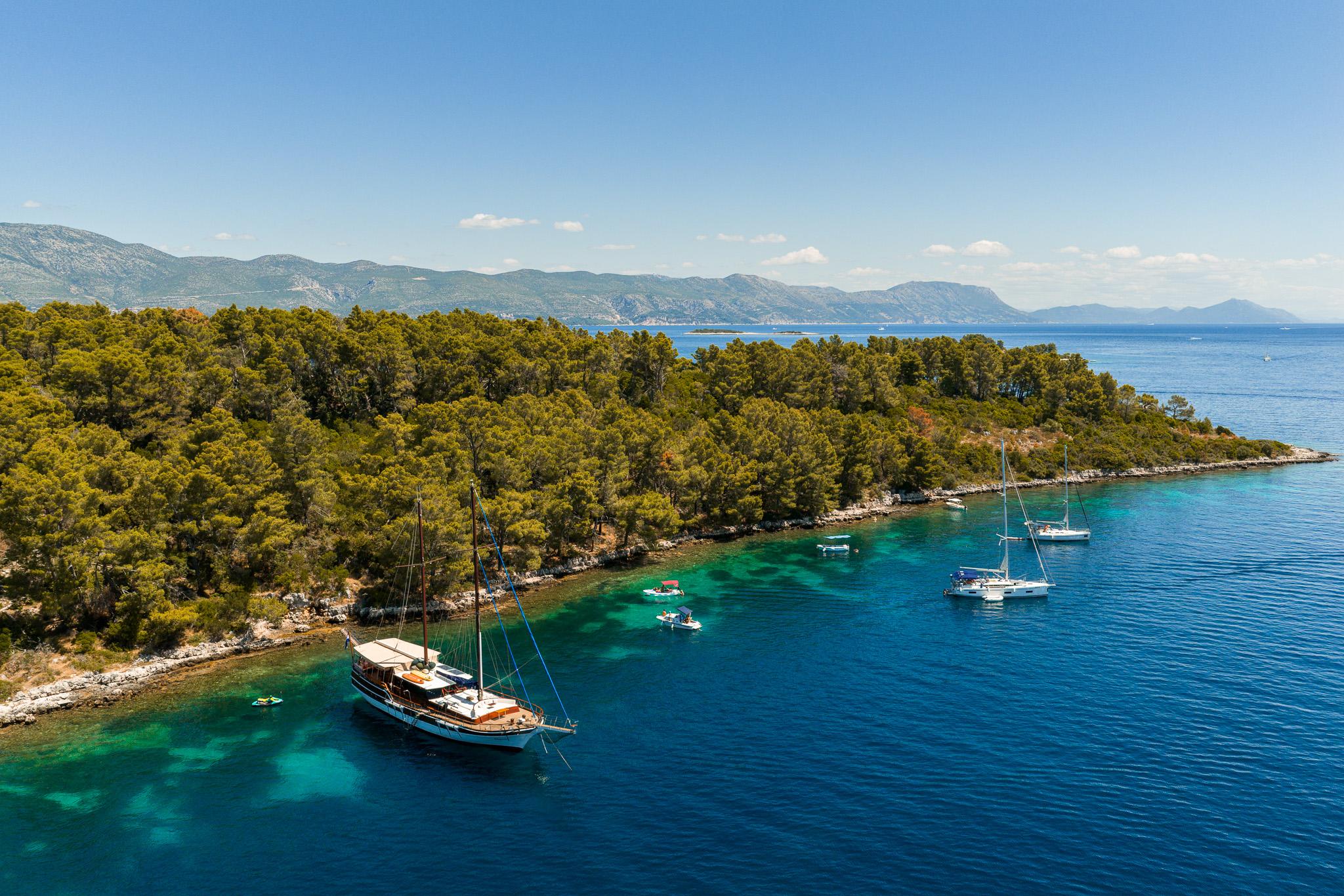 aerial drone shot of traditional gulet yacht anchored in crystal clear turquoise Mediterranean bay