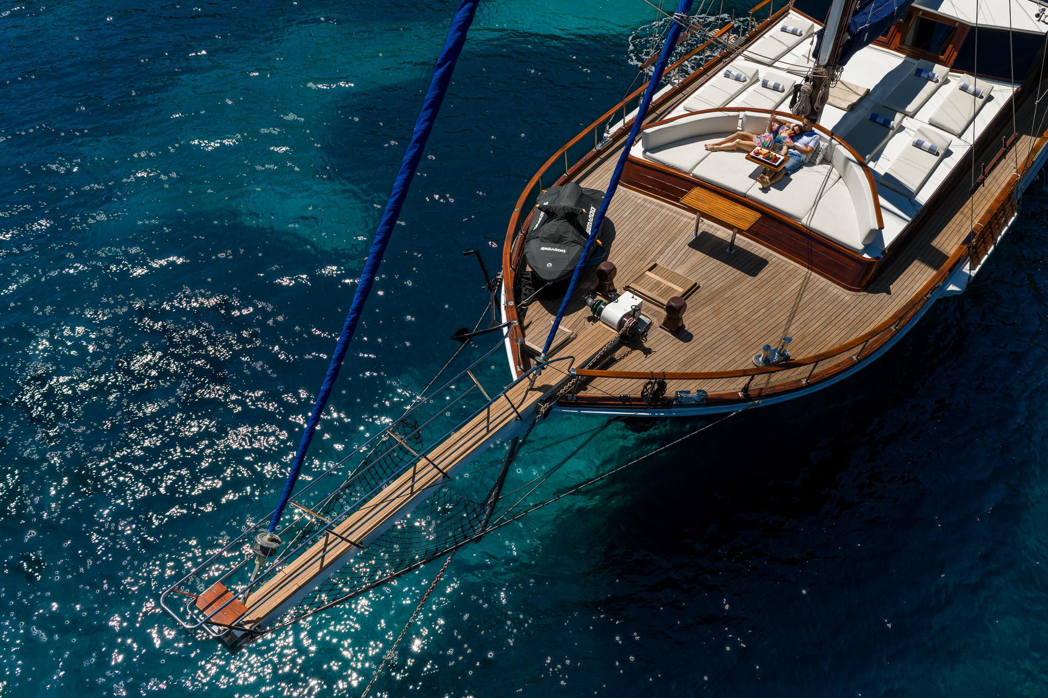 aerial view of wooden gulet stern showing swim platform and teak decking over crystal clear waters