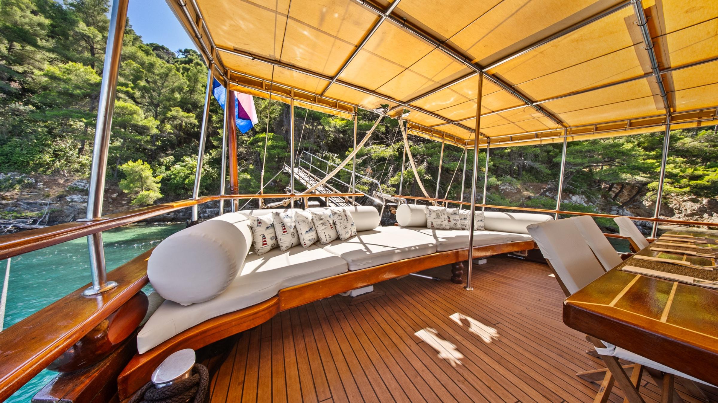 gulet bow deck with curved white cushioned seating under canvas awning