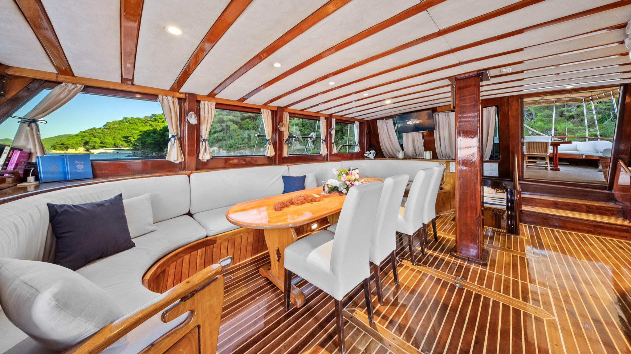 yacht interior salon with curved banquette seating, oval dining table, and panoramic windows