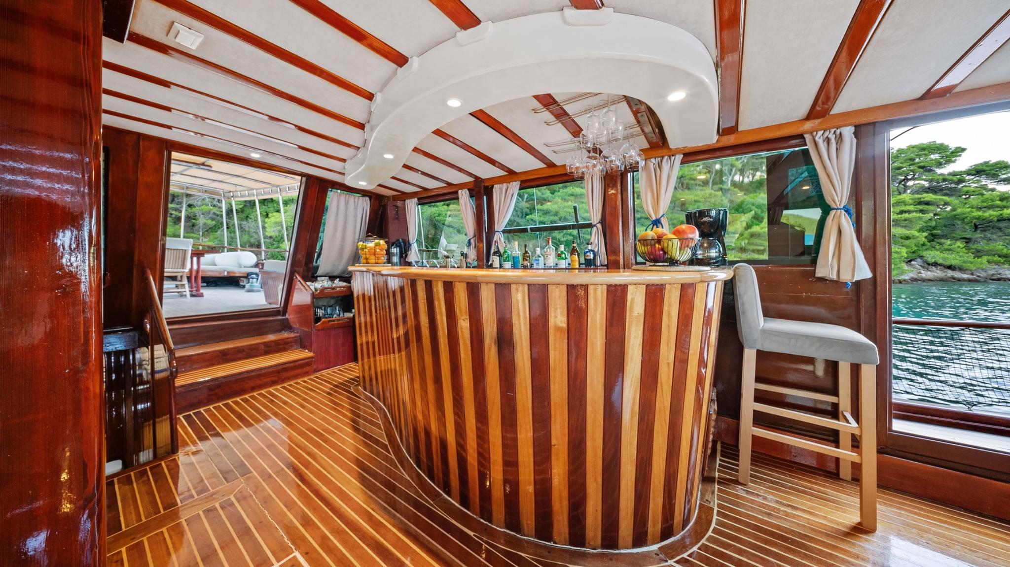 yacht interior salon featuring curved wooden bar with stools and panoramic windows