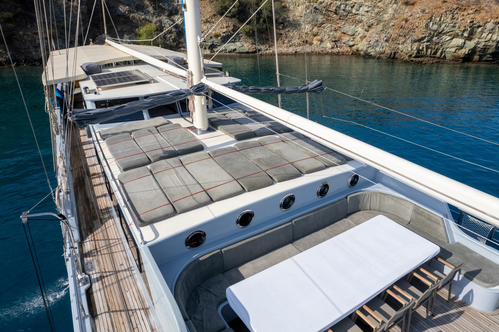 foredeck sun lounging area with gray cushioned mattresses and curved seating arrangement