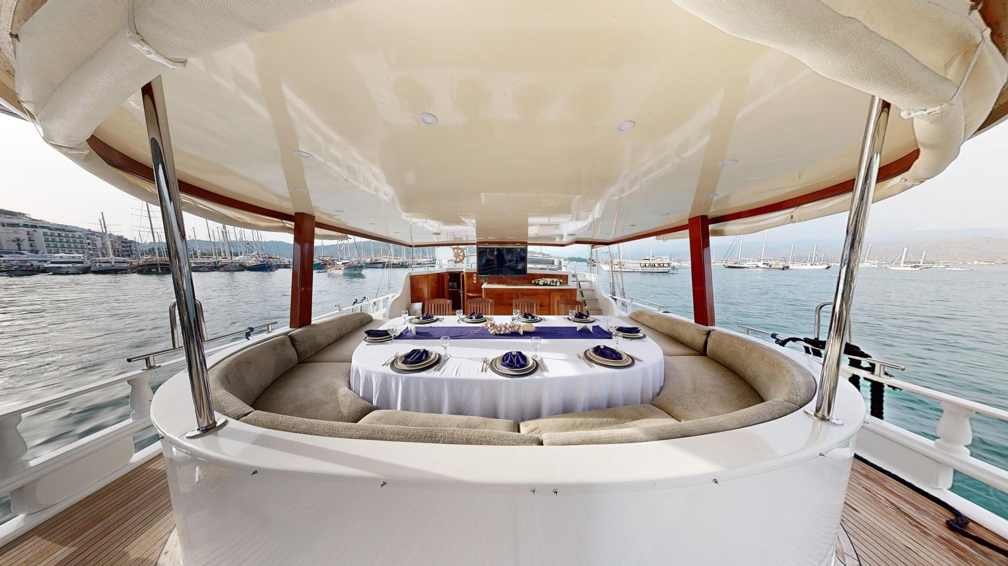 luxury yacht aft deck with circular dining table, formal place settings and panoramic harbor views