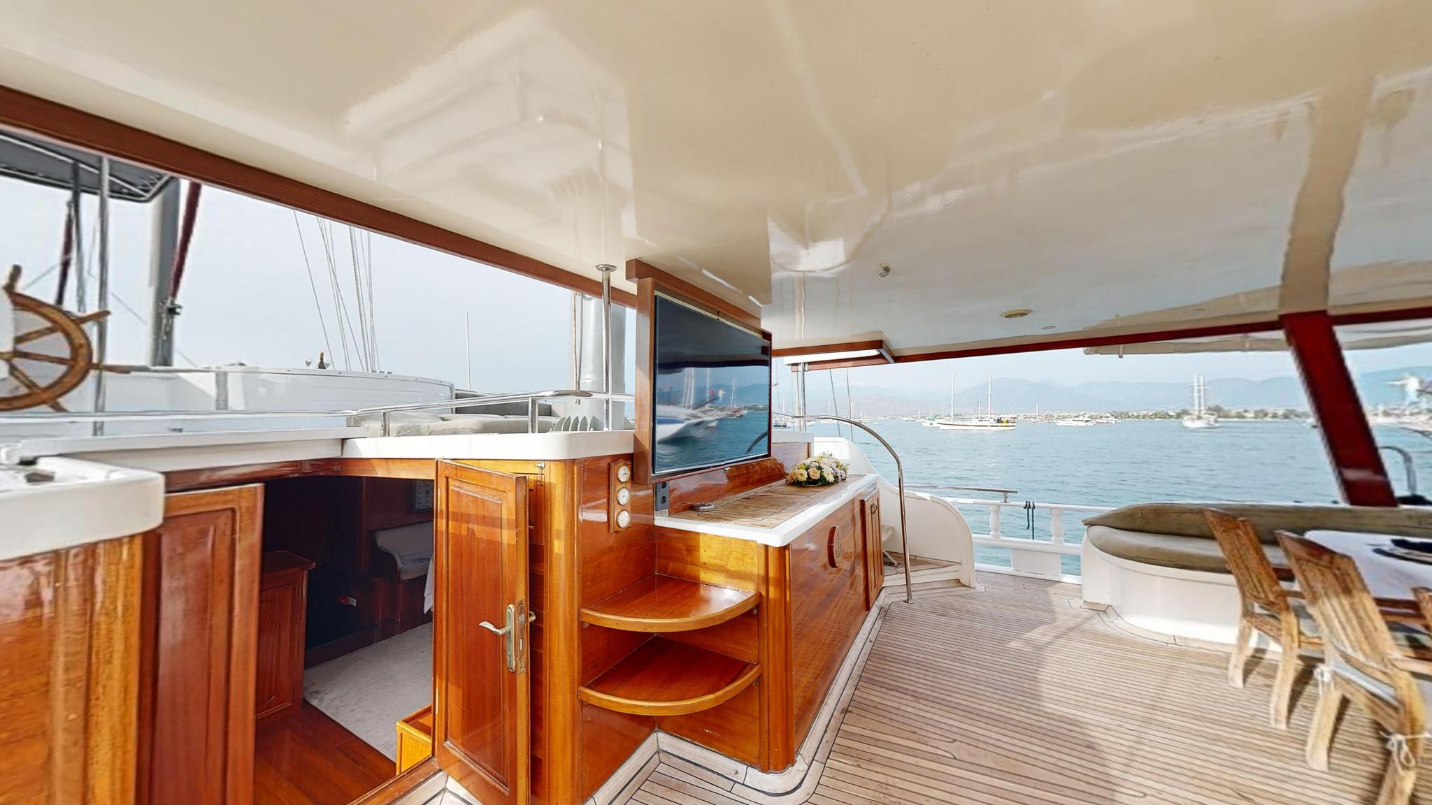 luxury yacht covered aft deck with wooden galley bar, seating area and marina views